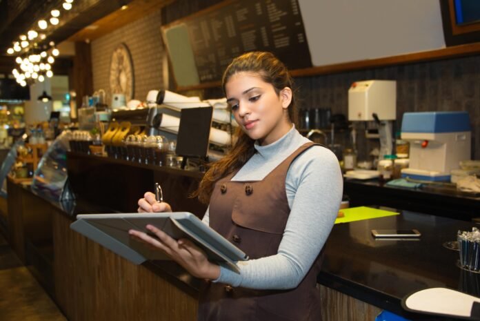confident-cafe-owner-writing-register-book-min